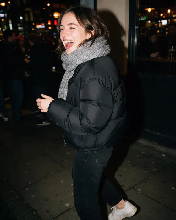Black puffer jacket and a grey scarf outside a bar at night